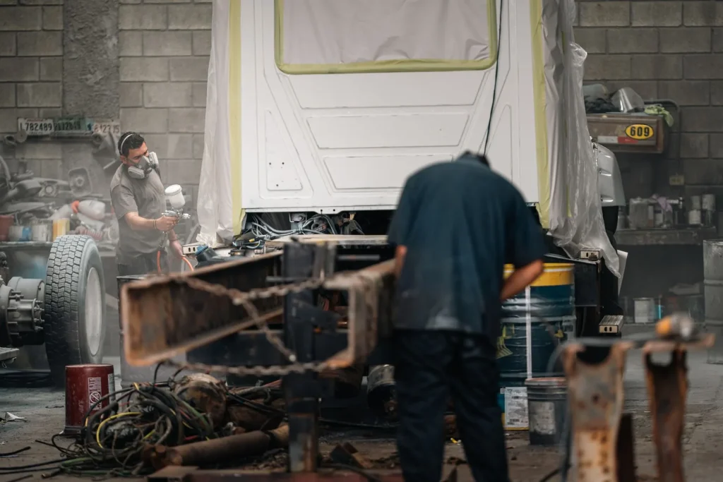 Two painters spraying a vehicle in protective gear
