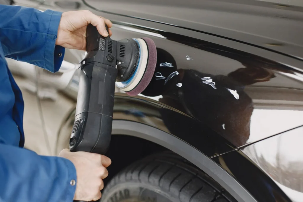 Machine polishing a car panel in a workshop