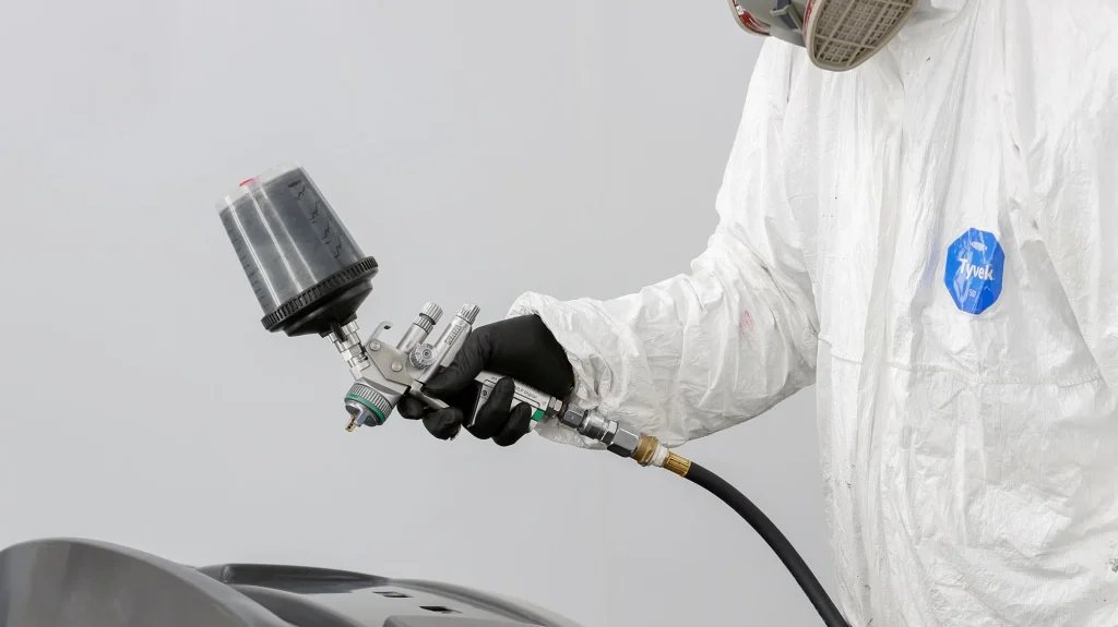 Painter spraying a primed bumper in the spray booth
