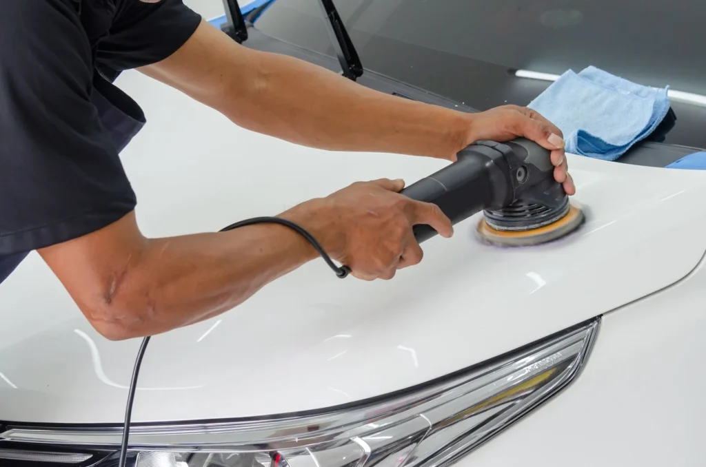 Rotary polisher working a white car bonnet