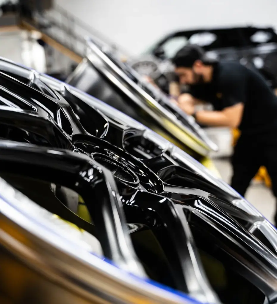 Polished alloy wheels with a technician working behind