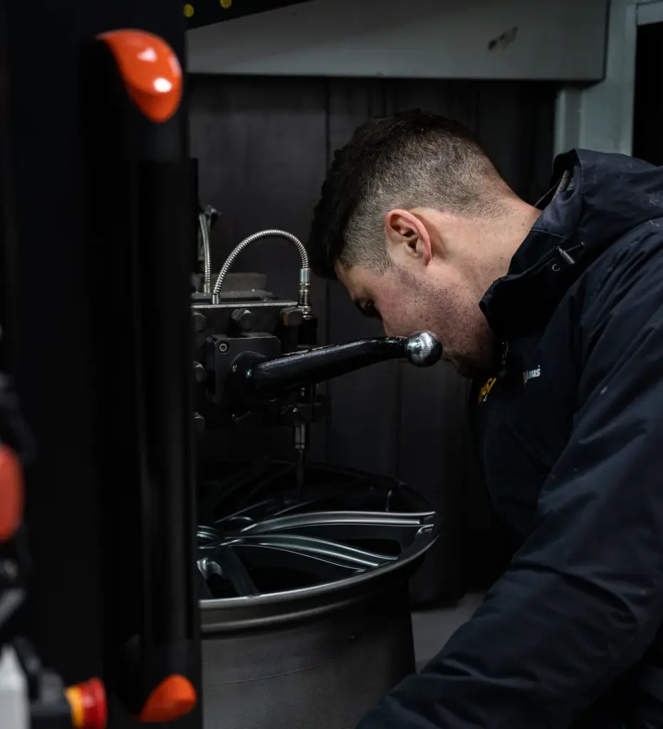A Whoops technician straightening a buckled alloy wheel
